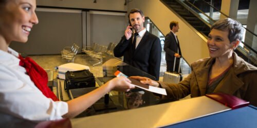 Female staff giving boarding pass to the passenger at the airport terminal